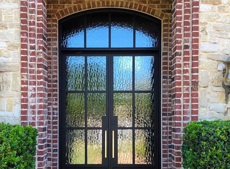 Black double door with glass panels in a brick and stone archway.