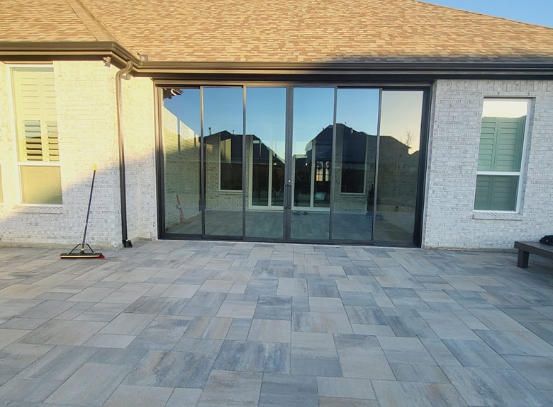 Modern house with large sliding glass doors and gray stone patio.
