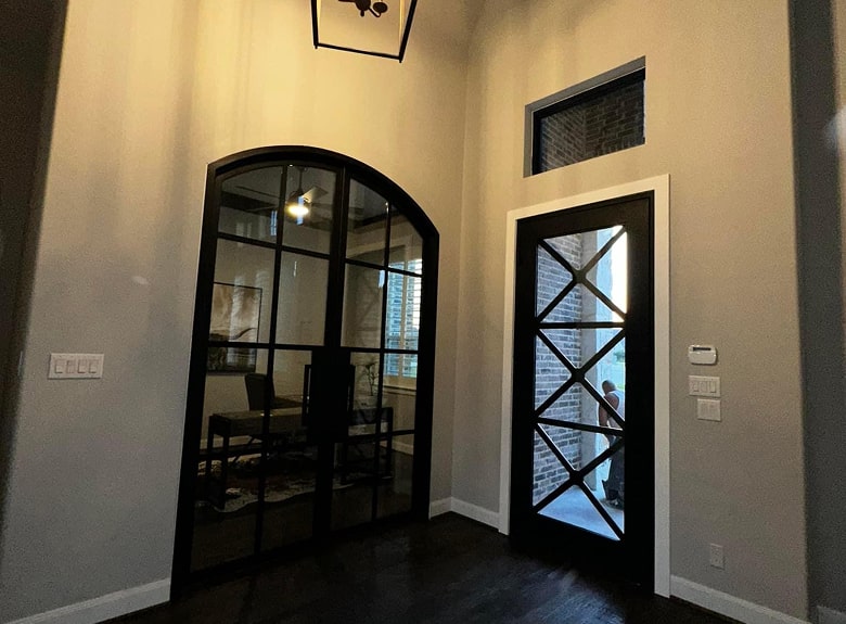 Foyer with black-framed arched double doors leading to a home office, and a crisscross front door.